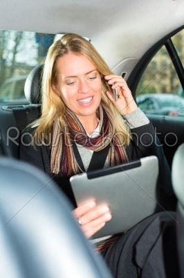 Woman going by taxi, she is on the phone