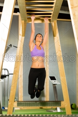 Woman hanging at high or horizontal bar