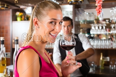 Woman holding a glass of wine in hand at the bar 