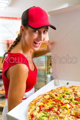 Woman holding a whole pizza in hand