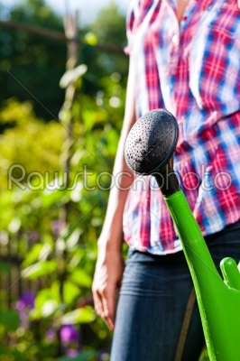 Woman in garden with watering can in hand