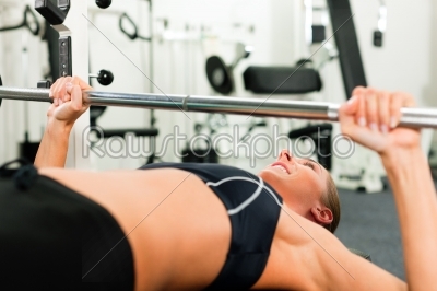 Woman in gym exercising with barbell