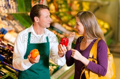 Woman in supermarket and shop assistant