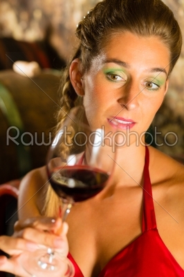 Woman looking at red wine glass in cellar