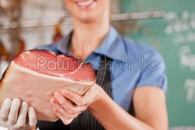 Woman or female butcher with raw ham in butchers shop