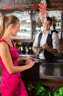 Woman ordering glass of wine at bar