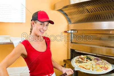 Woman pushing the pizza in the oven