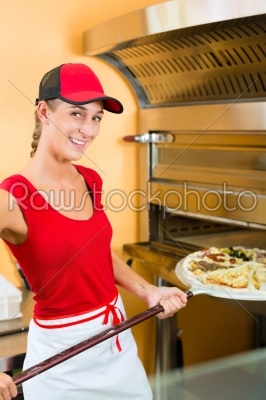 Woman pushing the pizza in the oven