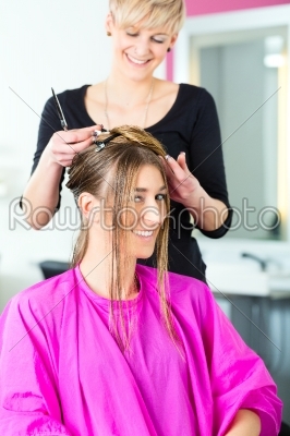 Woman receiving haircut from hair stylist or hairdresser