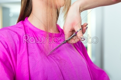 Woman receiving haircut from hairdresser or stylist