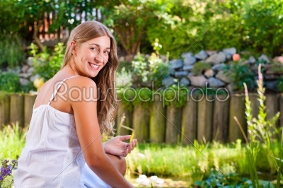 Woman sitting at pond in her garden