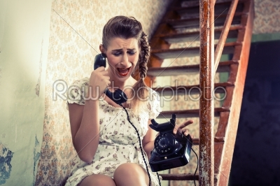Woman sitting on the stairs and crying on the phone