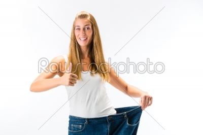 Woman standing and wearing a too big pants after loosing weight