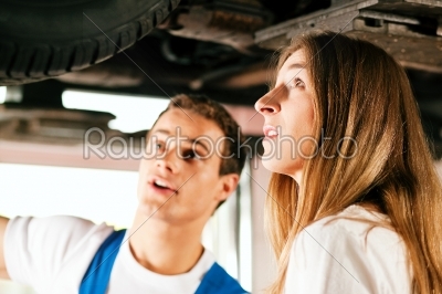 Woman talking to car mechanic in repair shop