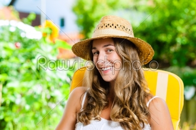 Woman tanning in her garden on lounge chair