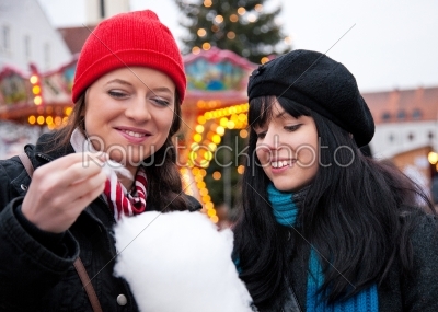 Women on Christmas market eating candy