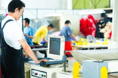 Worker on a machine in asian factory