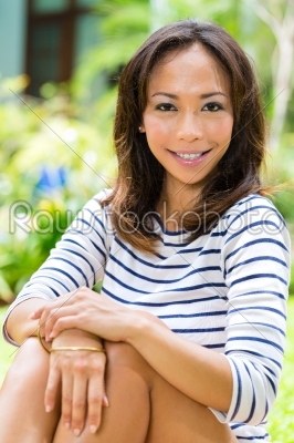 Young Asian woman at home in garden reading