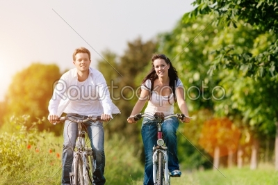 young couple cycling with bicycle in summer