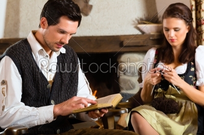 Young couple in mountain hut at fire place