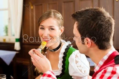 Young couple in traditional Bavarian Tracht eating in restaurant or pub