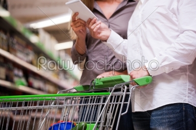 Young couple shopping together with trolley at supermarket