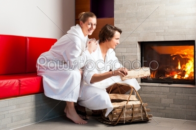 Young couple sitting in bathrobe for open fireplace