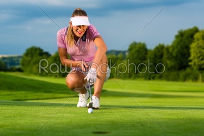 Young female golf player on course aiming for her put