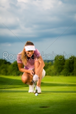 Young female golf player on course aiming for her put