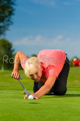 Young female golf player on course aiming for put