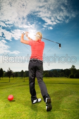 Young golf player on course doing golf swing