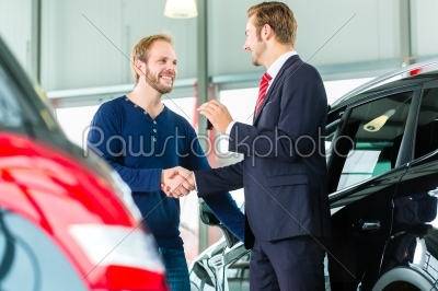Young man and seller with auto in car dealership