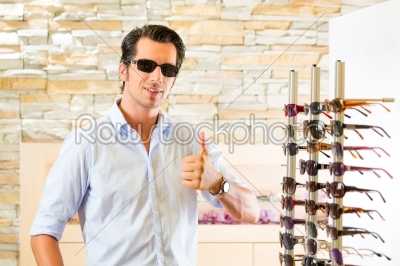 Young man at optician buying sun glasses