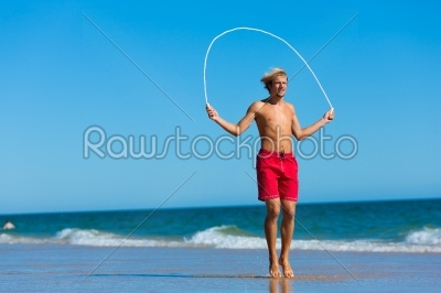 Young man jumping rope at the beach