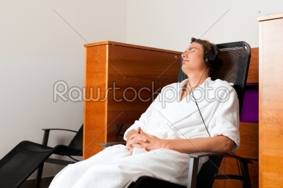 Young man relaxing in spa with music