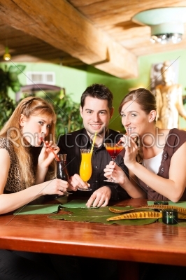 Young people drinking cocktails in bar or restaurant