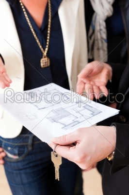 Young realtor explaining ground plan to couple