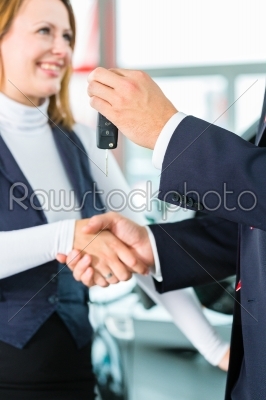 Young woman and seller with auto in car dealership