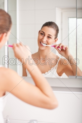 Young woman brushing teeth at wash bowl 