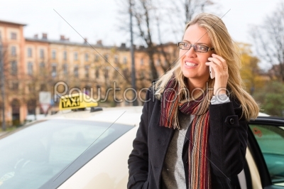 Young woman in front of taxi with phone