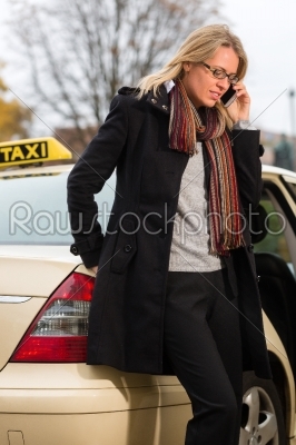 Young woman in front of taxi with phone