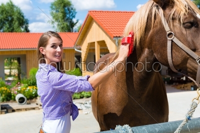 Young woman in the stable with horse