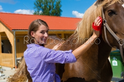 Young woman in the stable with horse