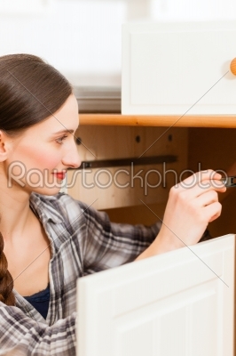 Young woman is assembling a cupboard