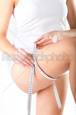 Young woman measuring her thigh