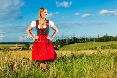 Young woman on meadow wearing dirndl