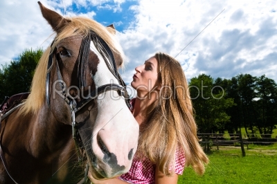 Young woman on the meadow with horse and kissing