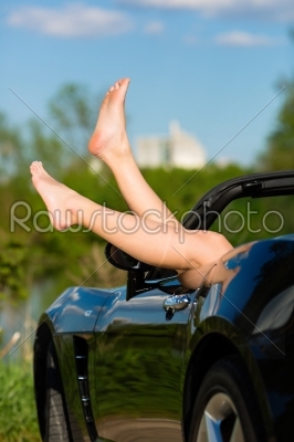 Young woman or her legs in a cabriolet