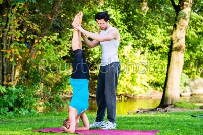 Young woman outdoors doing yoga with trainer