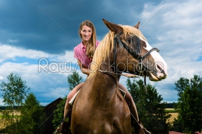 Young woman riding the horses on the meadow